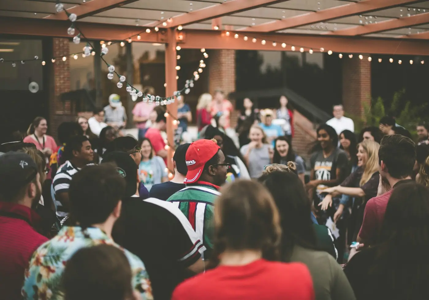 Guests at a community evening talking under string lights in the courtyard